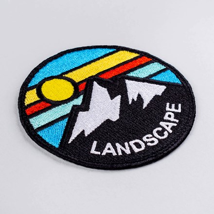 Embroidered mountain landscape patch laid at a hard angle