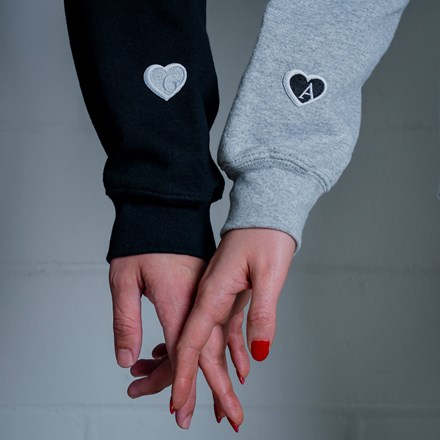 Close-up of Couple Holding hands with Embroidered Heart Patches Applied to Sweatshirt Sleeves